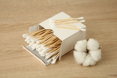 Photo of Cotton swabs and flower on wooden table, closeup