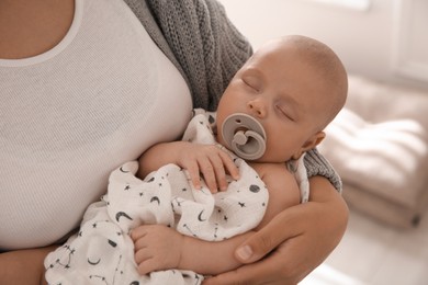 Photo of Mother holding her sleeping baby indoors, closeup