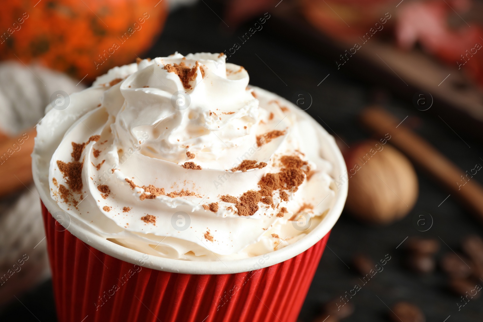 Photo of Paper cup with tasty pumpkin spice latte on wooden table, closeup