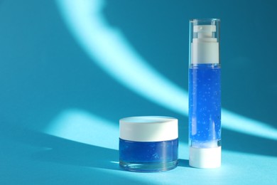 Photo of Bottle and jar of cosmetic products on light blue background. Space for text