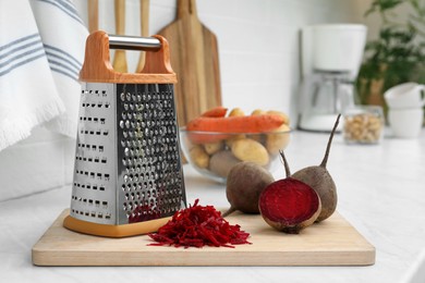 Photo of Grater and fresh ripe beetroots on kitchen counter