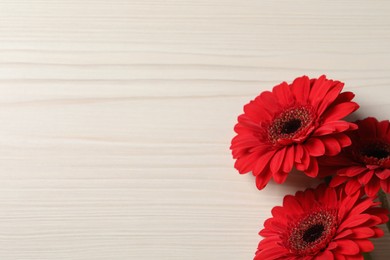 Photo of Bouquet of beautiful red gerbera flowers on wooden background, top view. Space for text