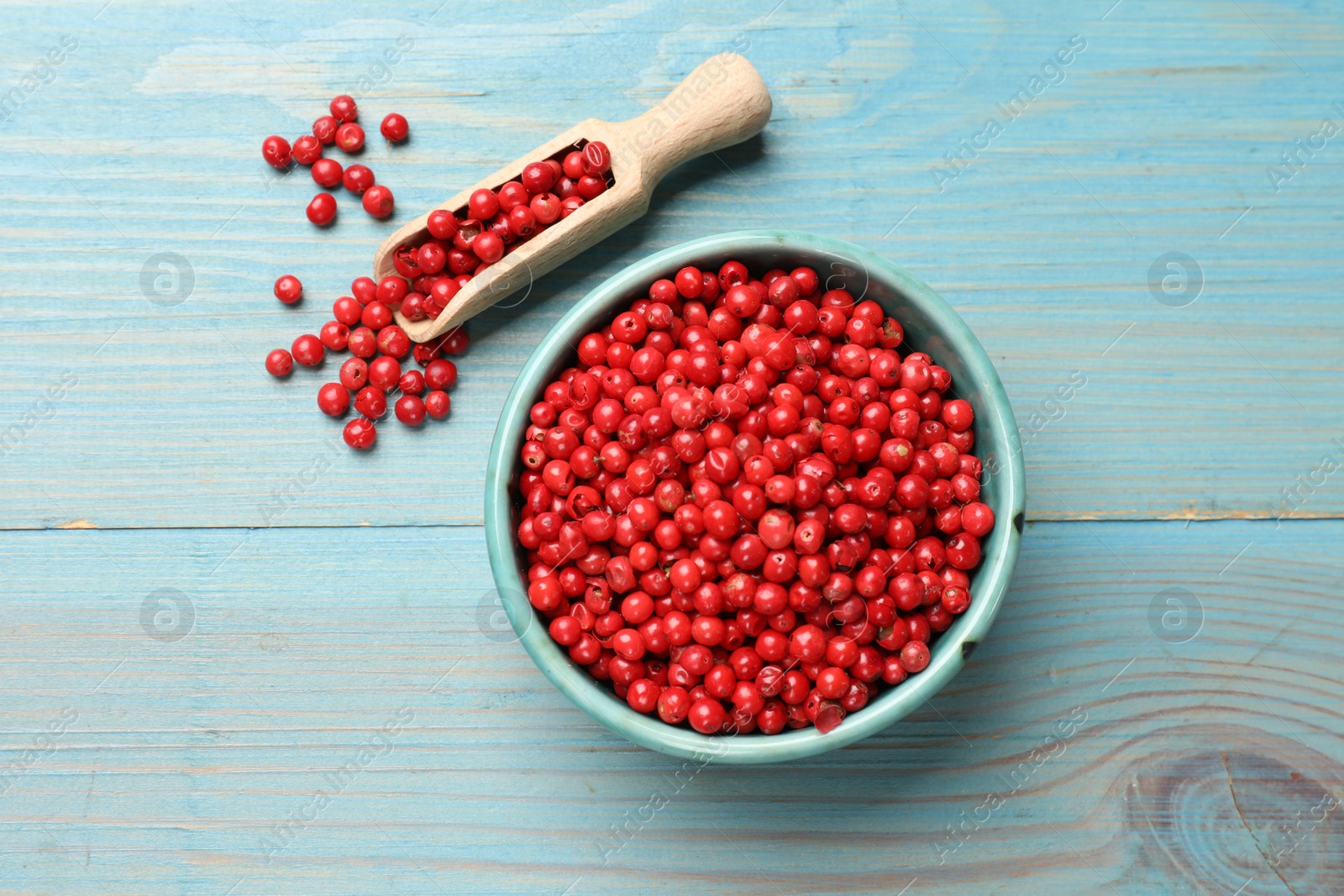 Photo of Aromatic spice. Red pepper in bowl and scoop on light blue wooden table, top view