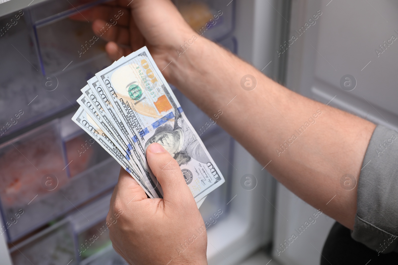 Photo of Man hiding money in refrigerator, closeup. Financial savings