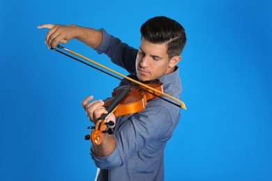 Man playing violin on light blue background