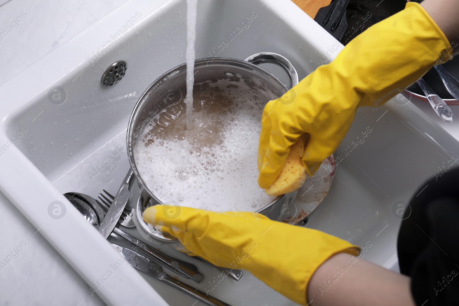 Photo of Woman washing dirty dishes in kitchen sink, closeup