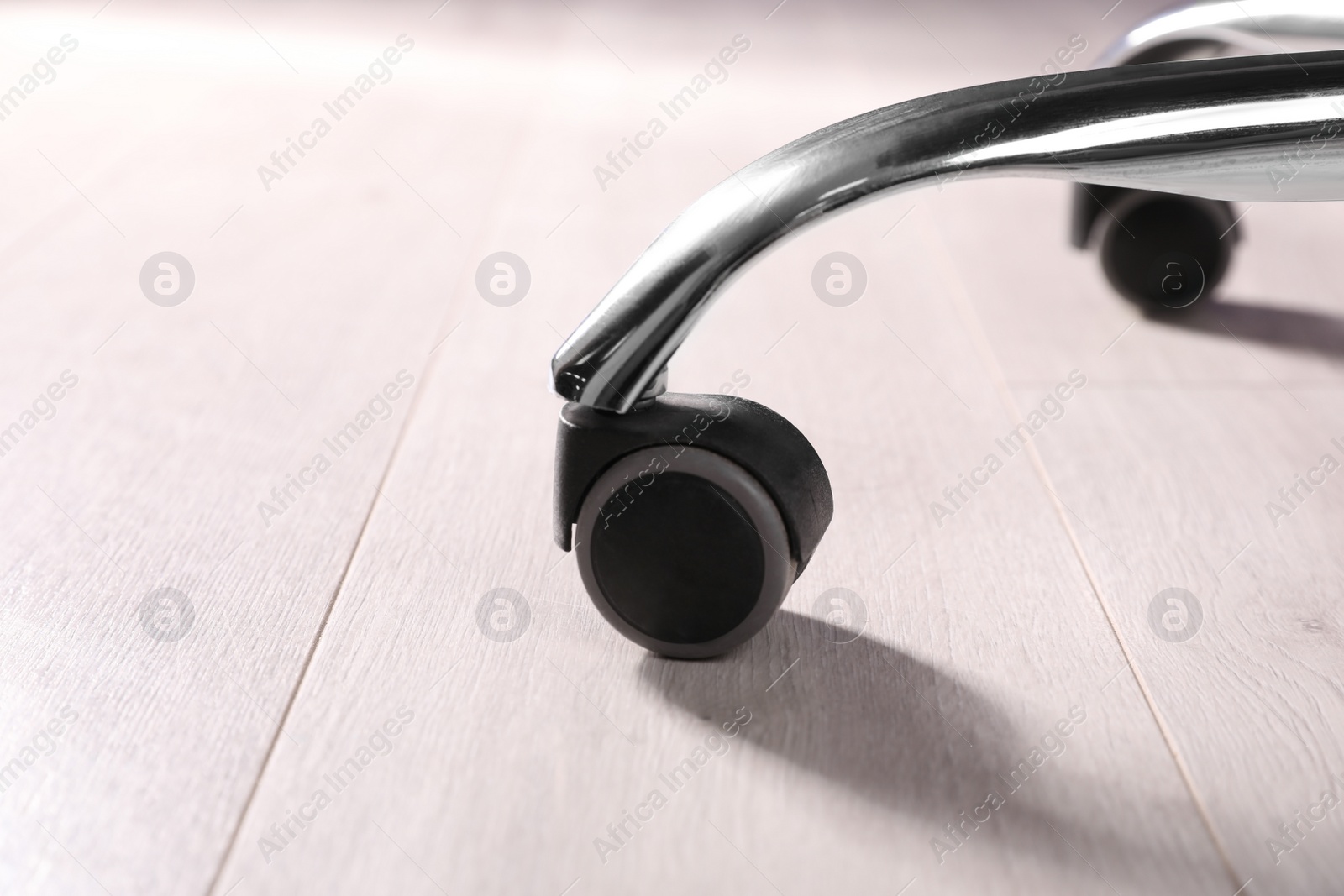 Photo of Modern office chair on wooden floor, closeup. Base with casters