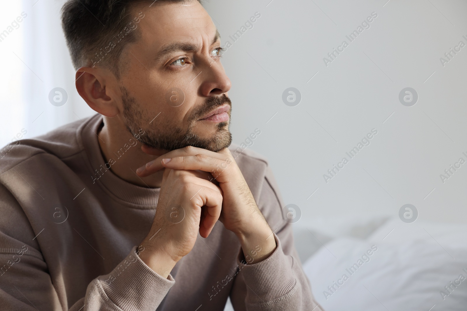 Photo of Upset man sulking at home, space for text. Loneliness concept