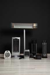 Photo of Set of different modern electric heaters near black wall