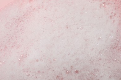 Photo of Fluffy soap foam on pink background, closeup