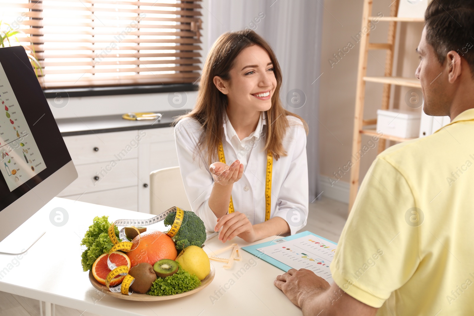 Photo of Young nutritionist consulting patient at table in clinic