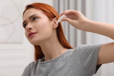 Photo of Woman applying medical ear drops at home