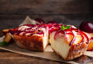 Photo of Delicious cake with plums on wooden table, closeup