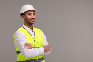 Engineer in hard hat on grey background, space for text