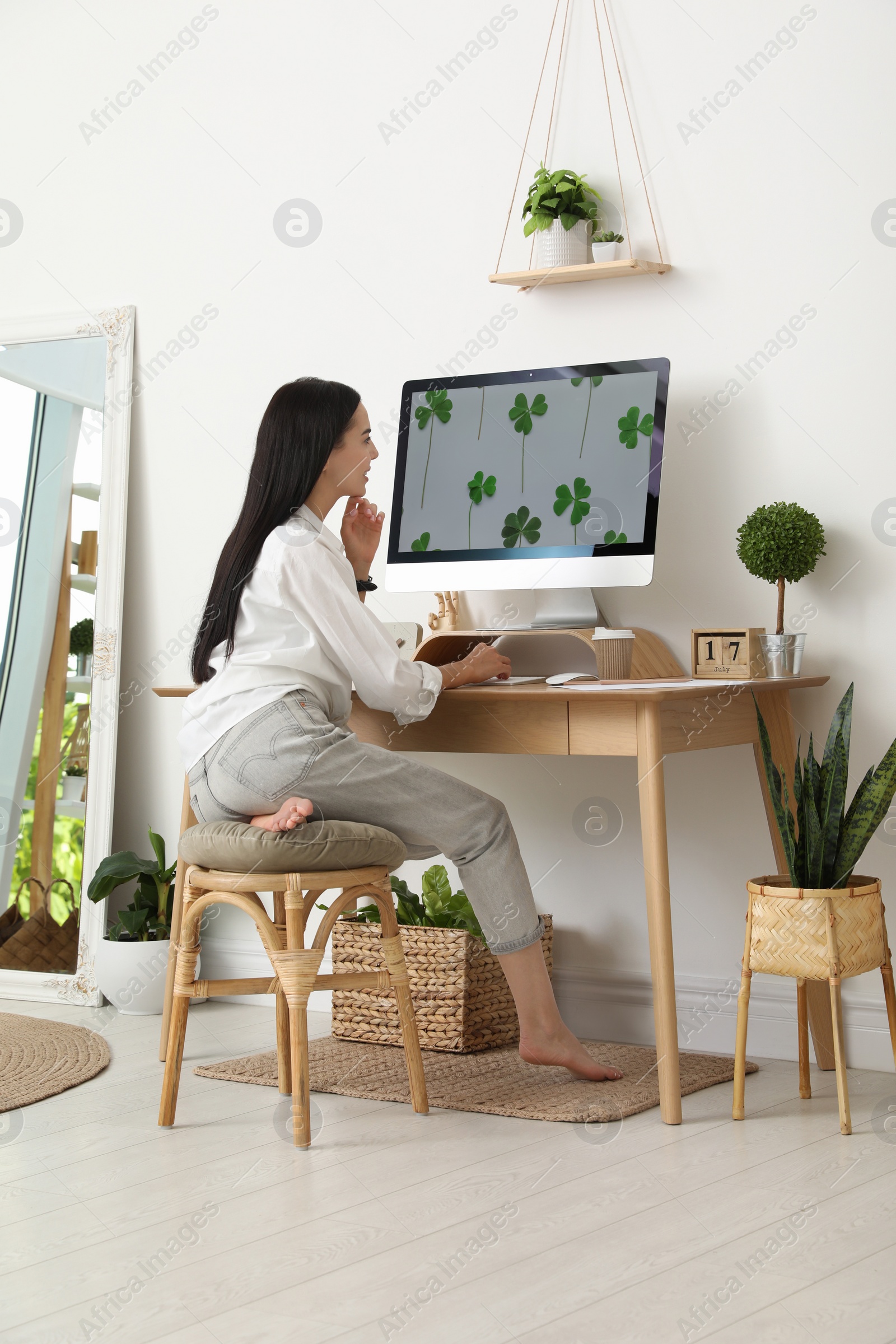 Photo of Young woman working at table in light room. Home office