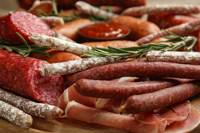 Different types of sausages served on wooden board, closeup