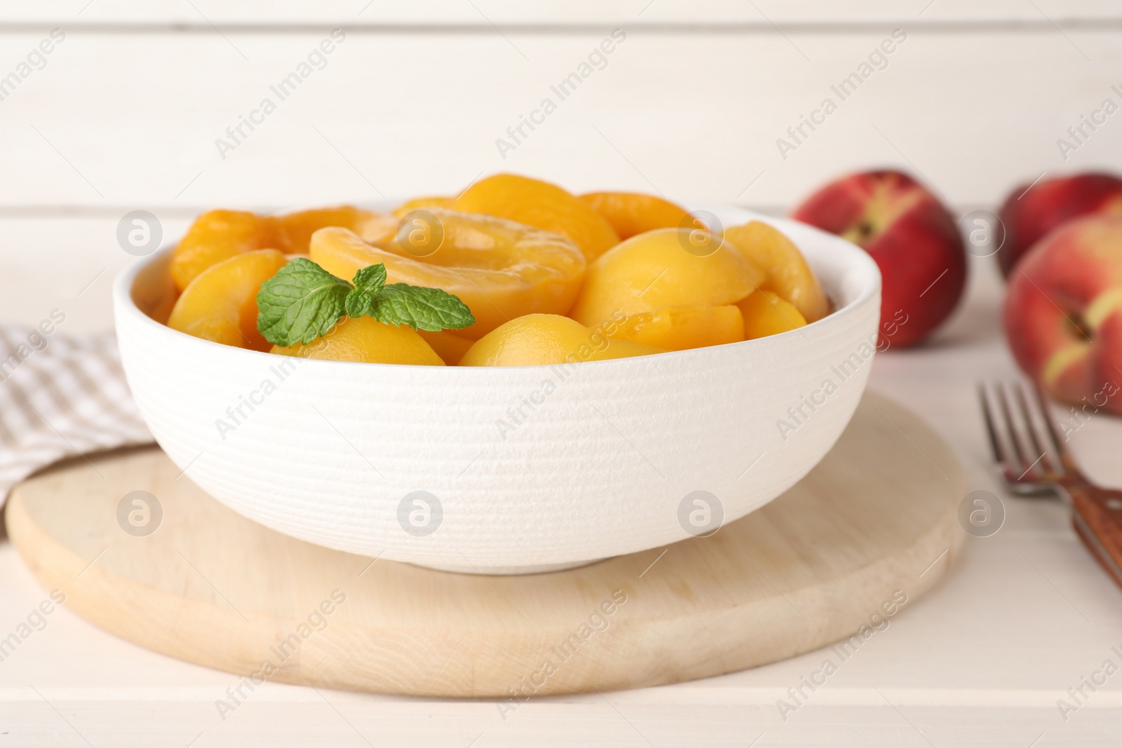 Photo of Canned peach halves in bowl on white table