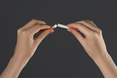 Photo of Stop smoking concept. Woman breaking cigarette on gray background, closeup