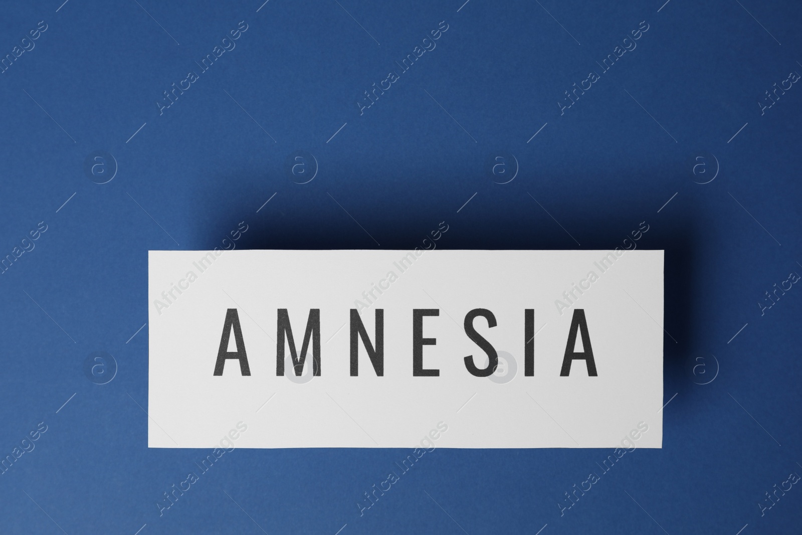 Photo of Card with word Amnesia on blue background, top view