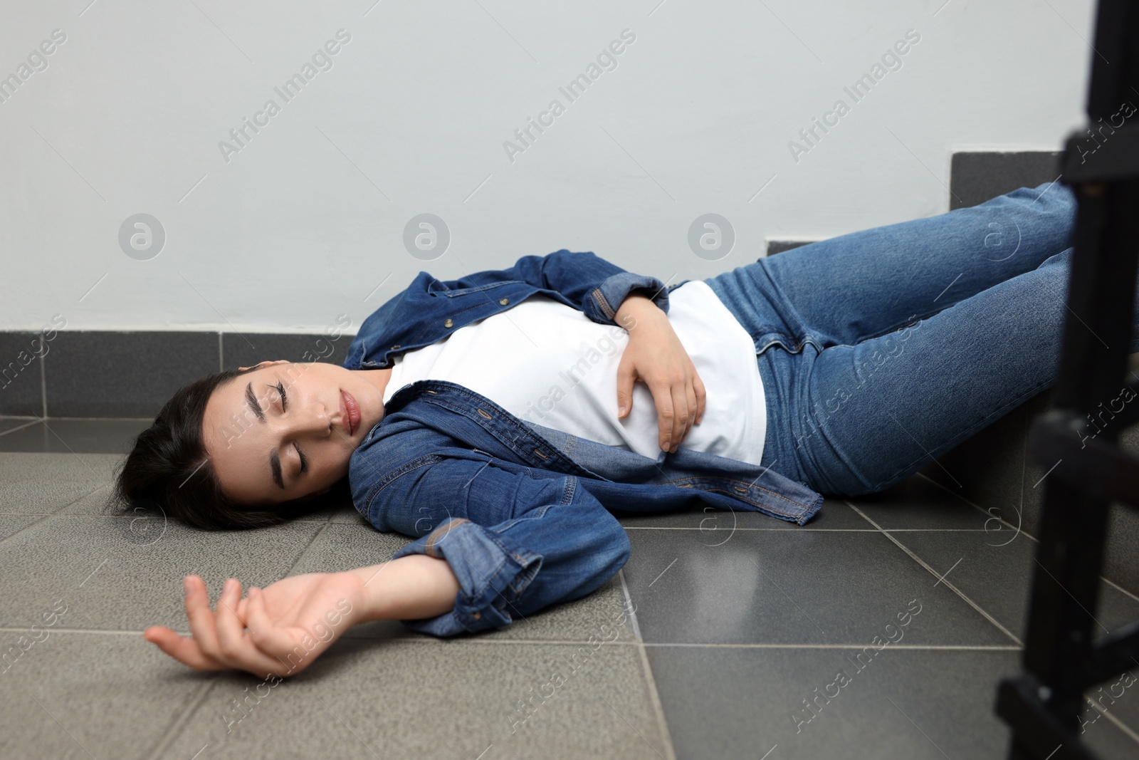 Photo of Unconscious woman lying on floor after falling down stairs indoors