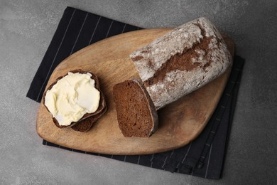 Photo of Tasty bread with butter on grey textured table, top view
