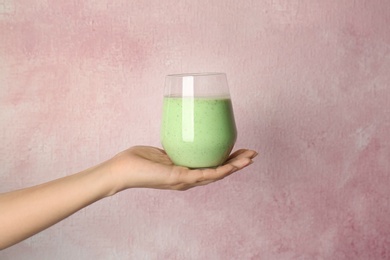 Woman holding glass with delicious smoothie on color background