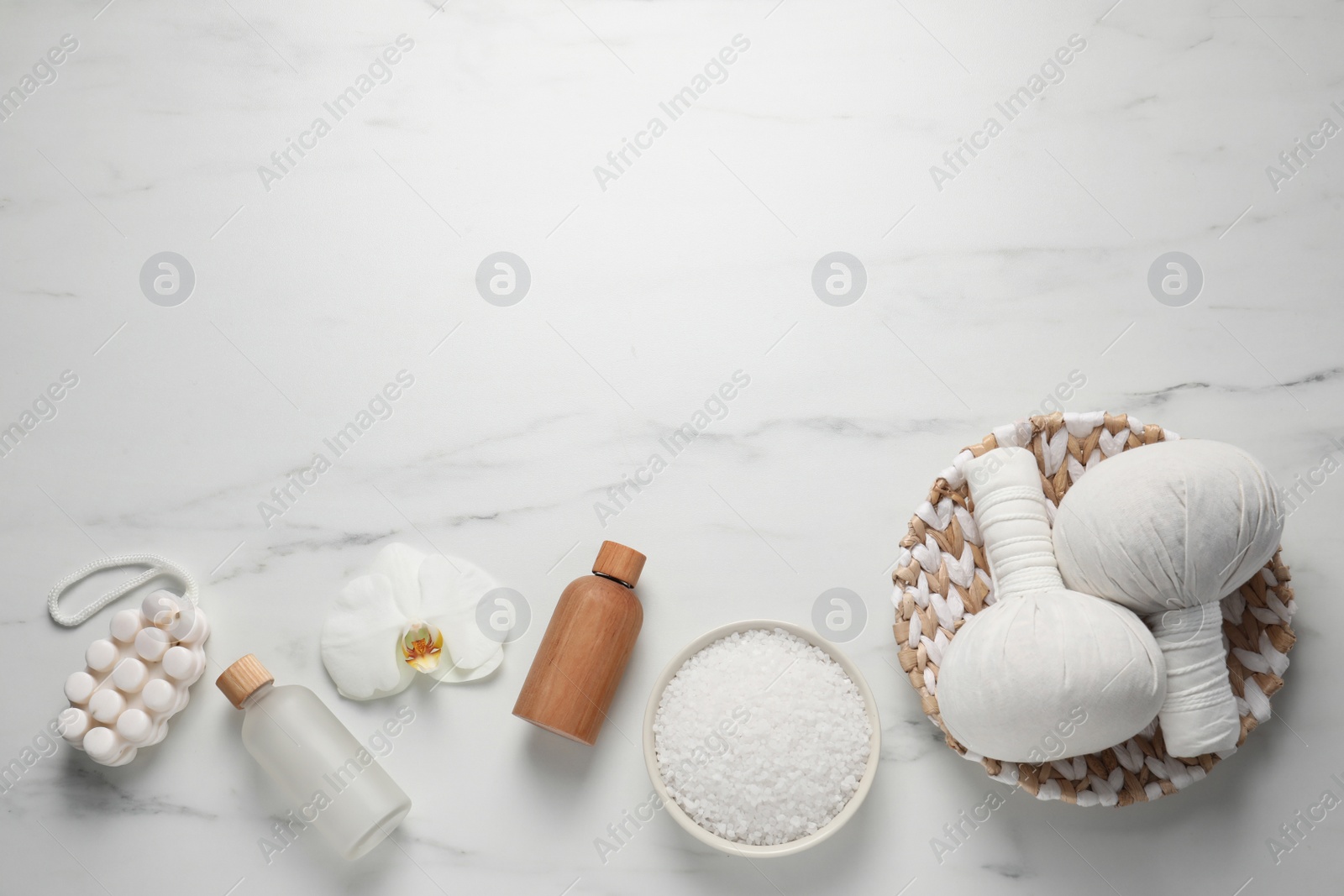 Photo of Flat lay composition with herbal massage bags and other spa products on white marble table. Space for text