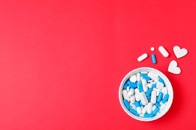 Flat lay composition with pills and hearts on color background, space for text. Cardiology concept