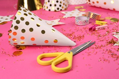 Party hat with confetti, scissors and different materials on pink background. Handmade decorations