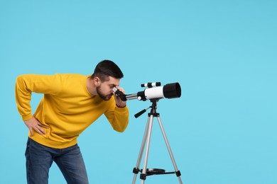 Photo of Astronomer looking at stars through telescope on light blue background. Space for text