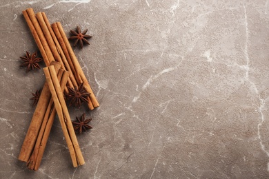 Aromatic cinnamon sticks and anise on grey marble table, flat lay. Space for text