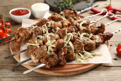 Photo of Metal skewers with delicious meat and onion served on wooden table