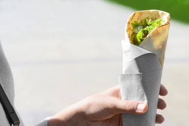 Woman holding delicious vegetable roll outdoors, closeup