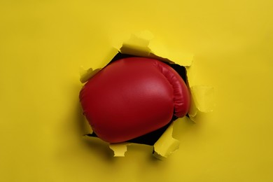 Photo of Man breaking through yellow paper with boxing glove, closeup