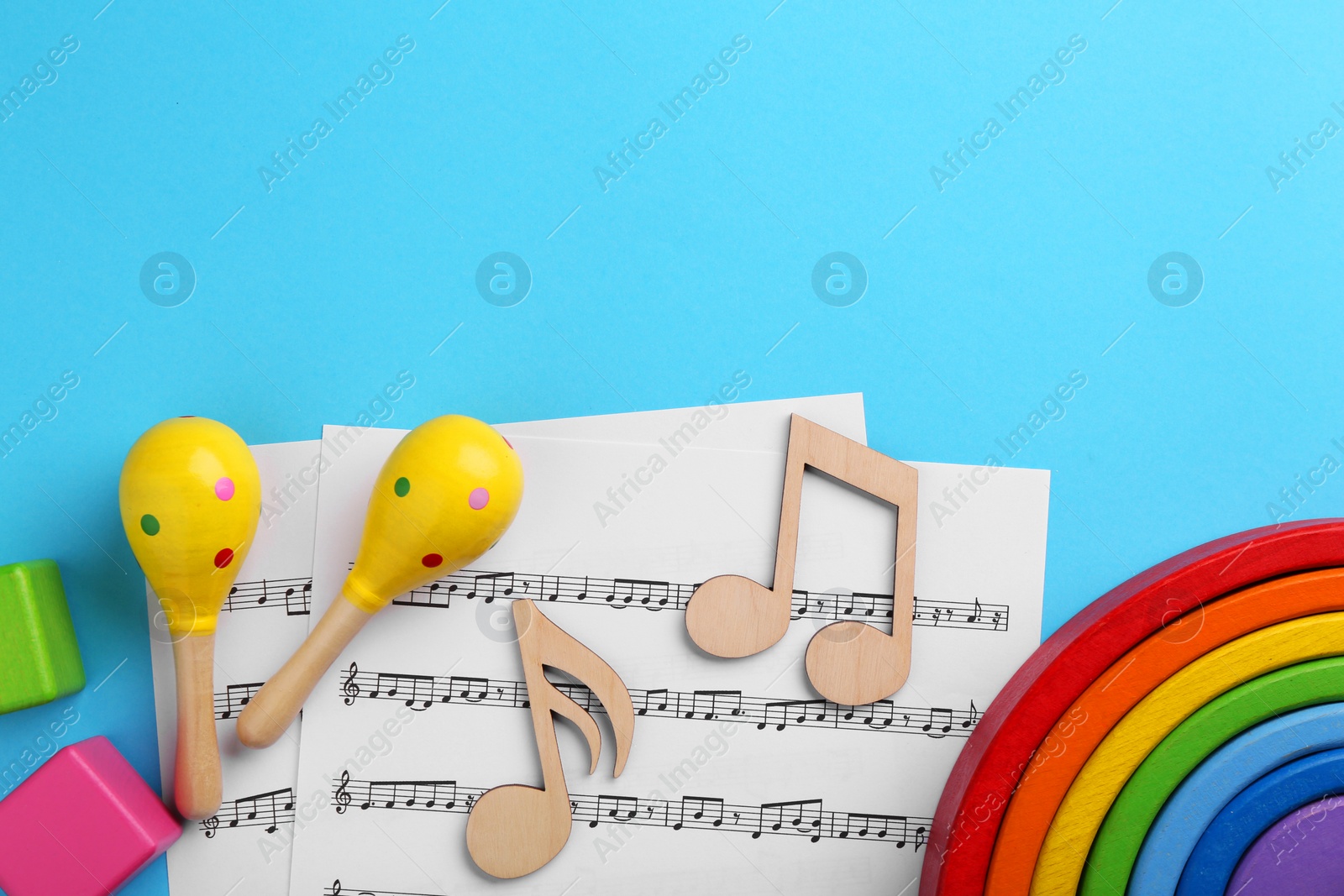 Photo of Tools for creating baby songs. Flat lay composition with wooden notes and maracas on light blue background