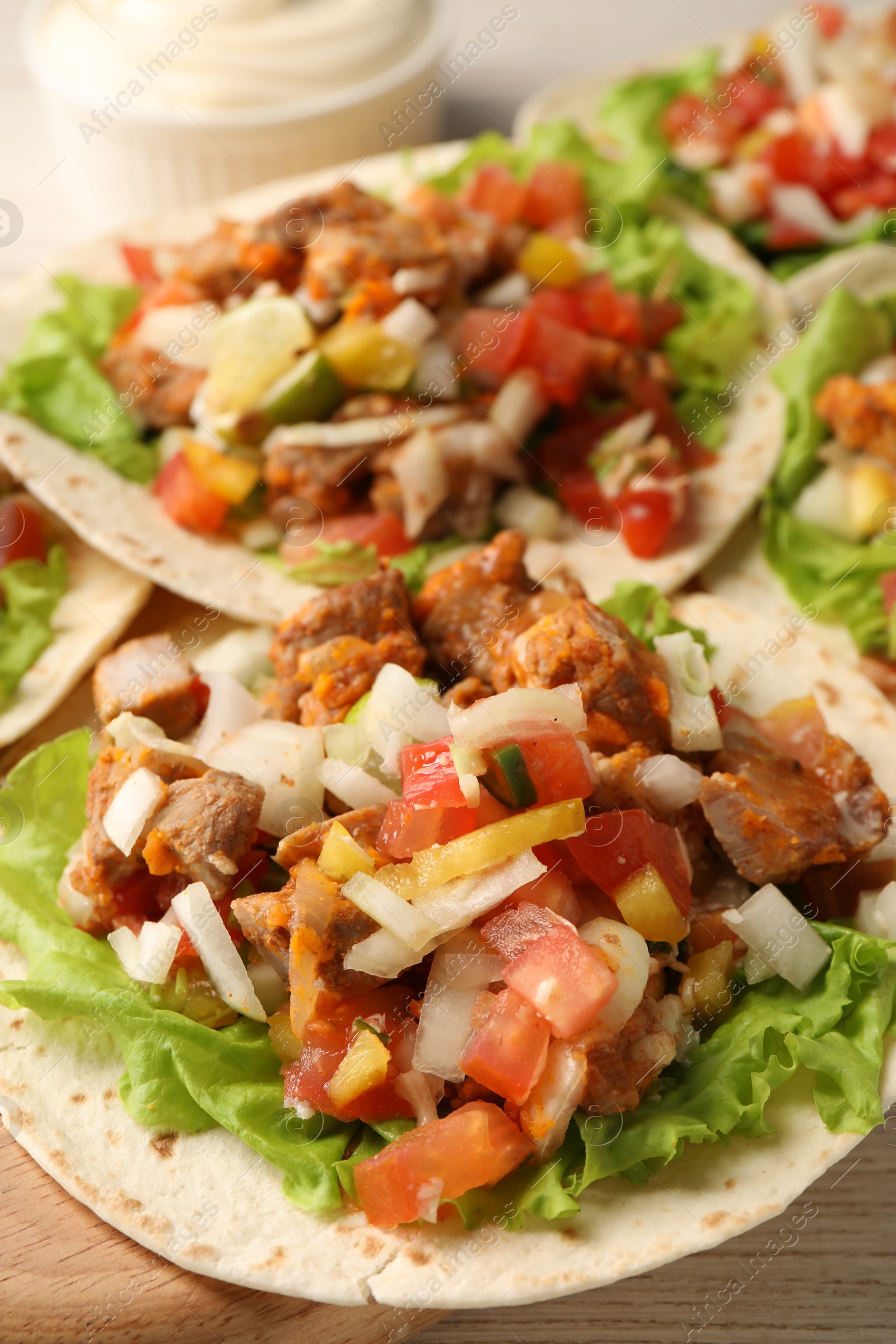 Photo of Delicious tacos with vegetables and meat on table, closeup