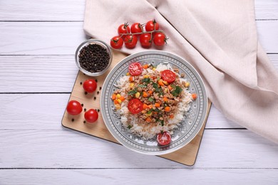 Tasty dish with fried minced meat, rice, carrot, tomatoes and corn on white wooden table, flat lay