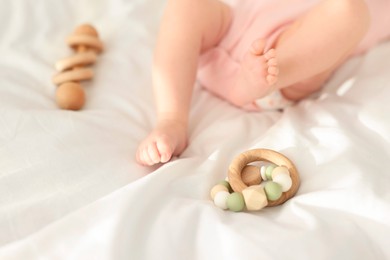 Cute baby and rattle toys on sheets, closeup