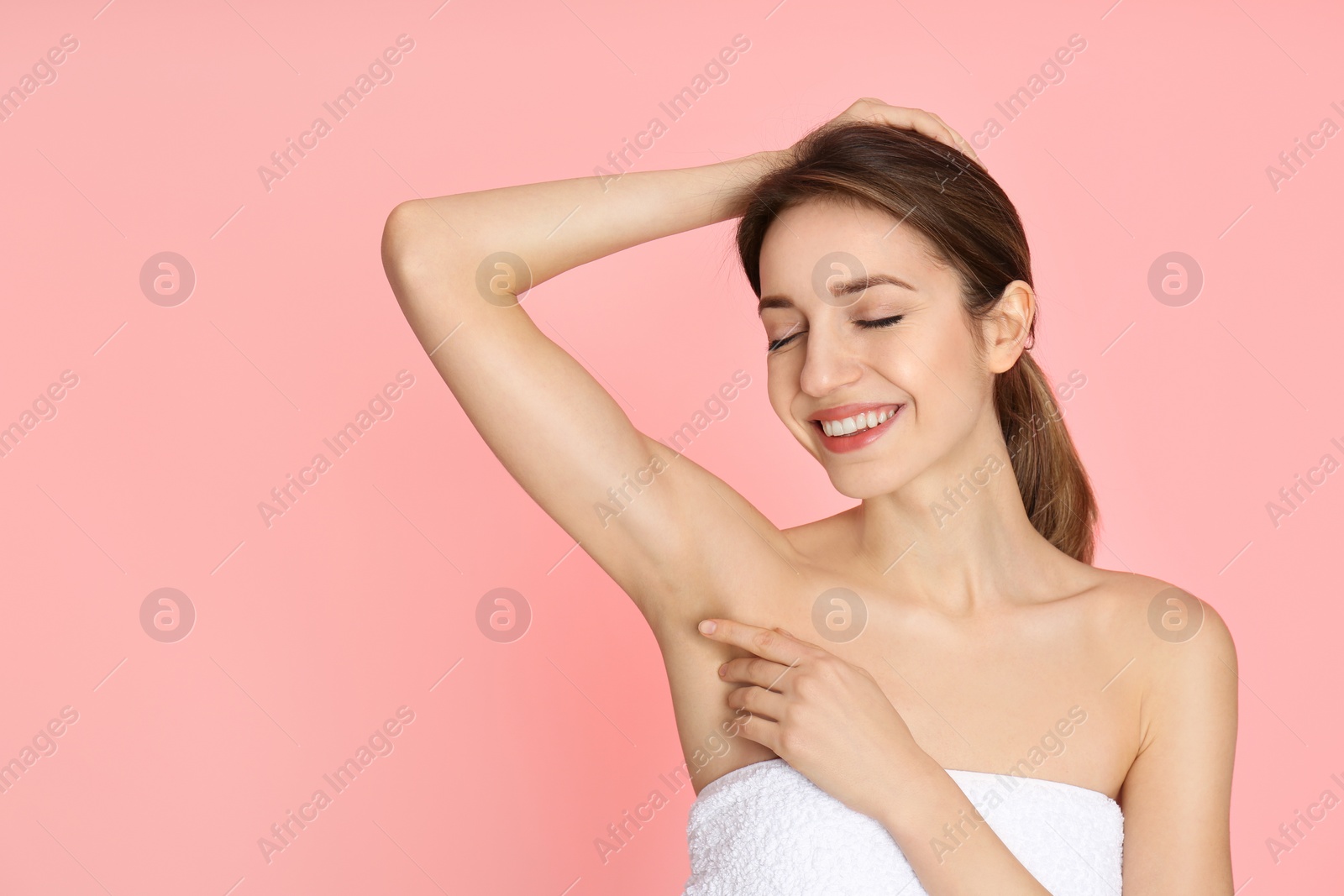 Photo of Young woman showing armpit with smooth clean skin on pink background, space for text