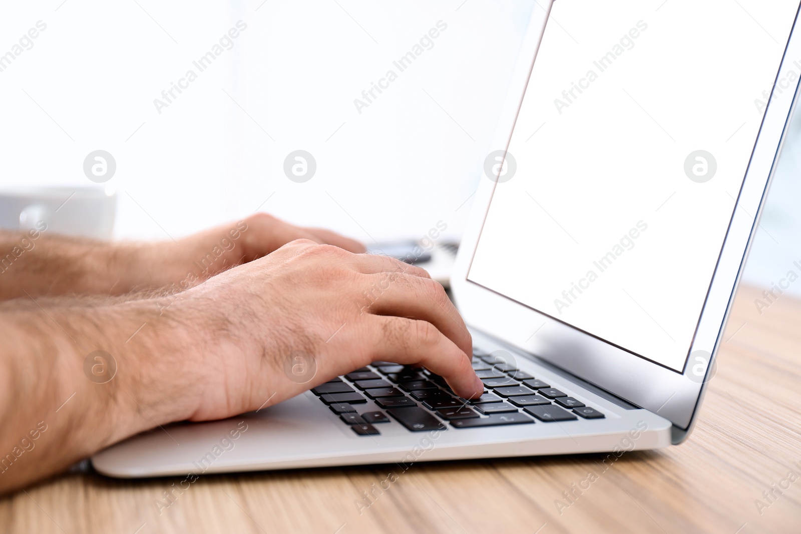 Photo of Man working with modern laptop at wooden table indoors, closeup