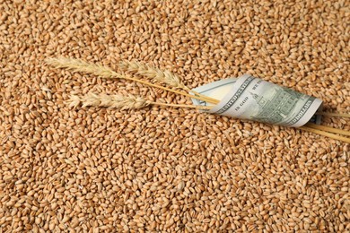 Photo of Dollar banknote and wheat ears on grains, top view. Agricultural business