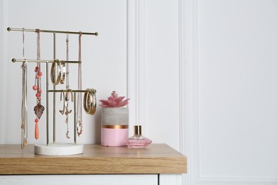 Interior element. Holder with set of luxurious jewelry and perfume on wooden dressing table. Space for text