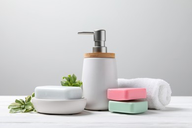Soap bars, bottle dispenser and towel on table against white background