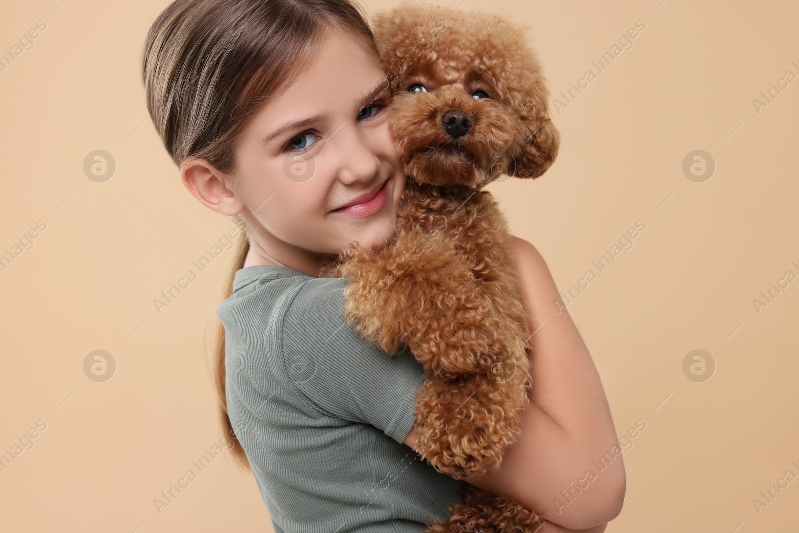 Photo of Little child with cute puppy on beige background. Lovely pet