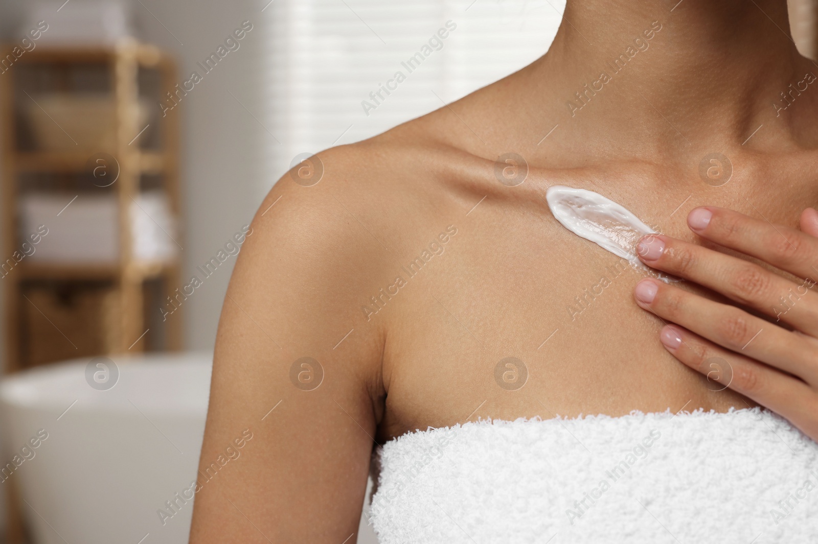 Photo of Woman applying cream onto body in bathroom, closeup. Space for text