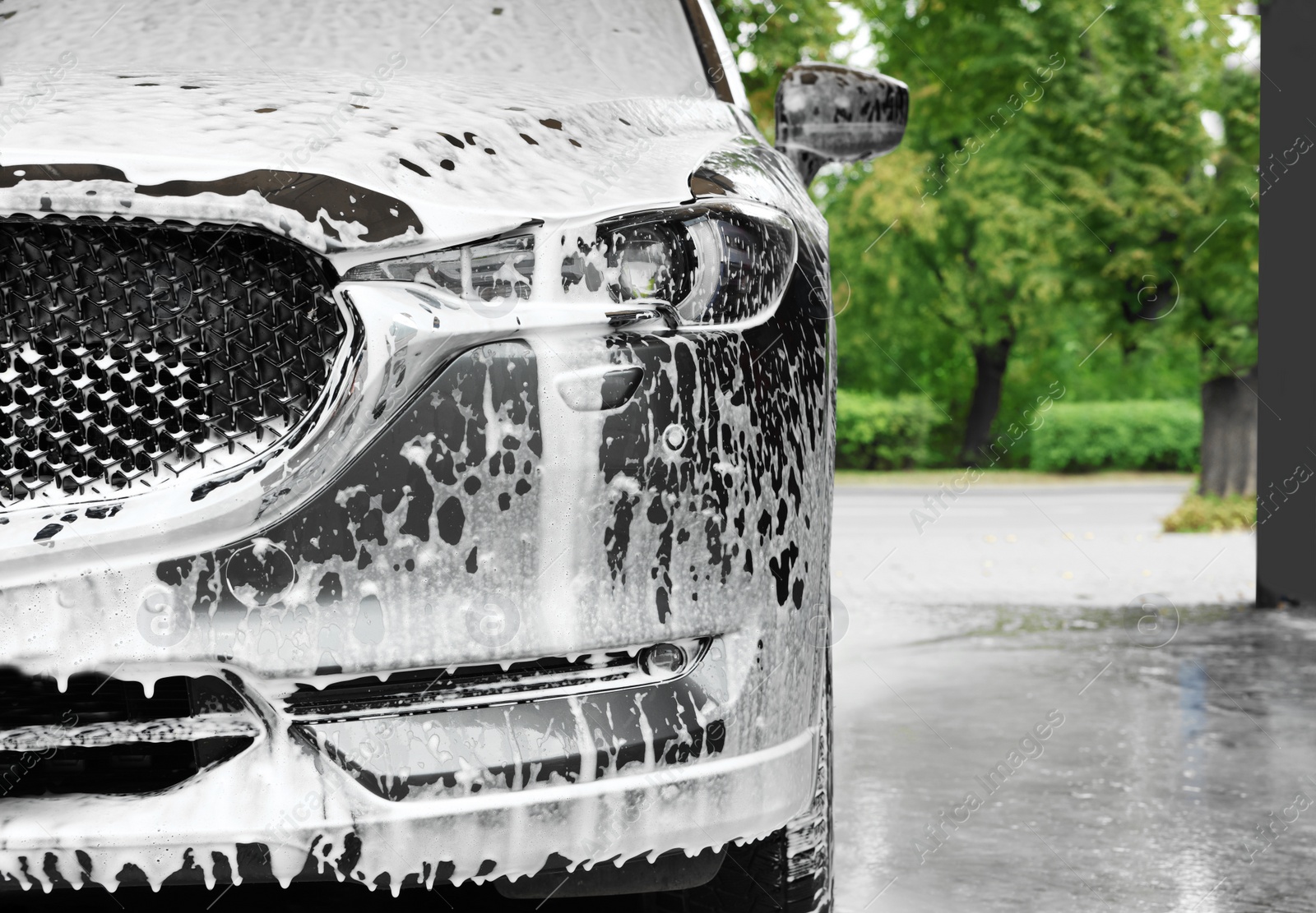 Photo of Auto with cleaning foam at car wash, closeup