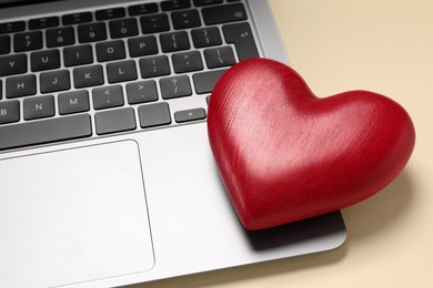 Photo of Long-distance relationship concept. Laptop and decorative heart on beige background, closeup