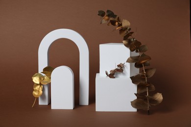 Photo of Autumn presentation for product. White geometric figures and golden branches with leaves on brown background