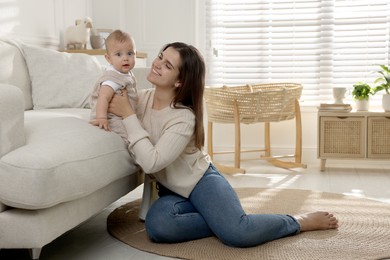 Photo of Happy young mother with her baby in living room. Space for text