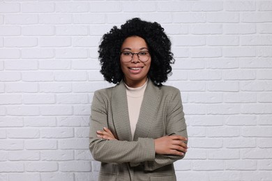 Young businesswoman in eyeglasses near white brick wall